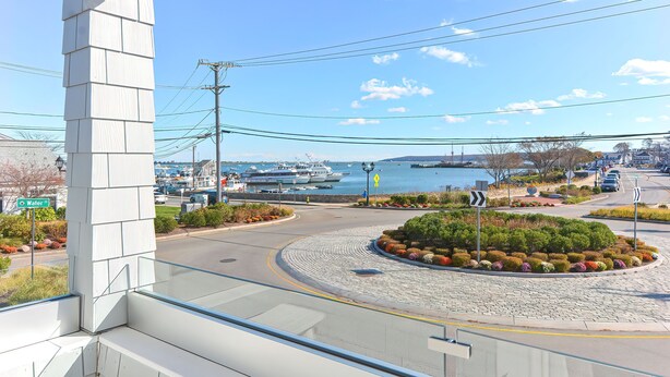 A view from a balcony overlooking a roundabout with a landscaped garden, a marina with boats, and a clear blue sky. - Harbourtown Suites (Plymouth)