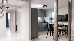 A modern kitchen with grey cabinets, a black countertop, and a dining area with a table and chairs. - Foundry Hotel Apartments (Uppsala)