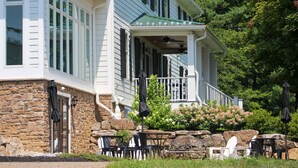 A two-story building with a porch, stone foundation, and outdoor seating area with tables and chairs. - Inn at Mary's Land Farm (Clarksville)