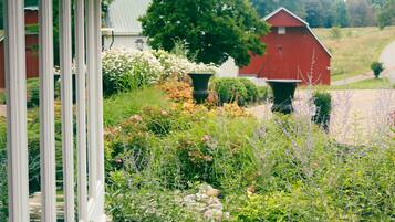 A red barn surrounded by a garden with various plants and flowers.