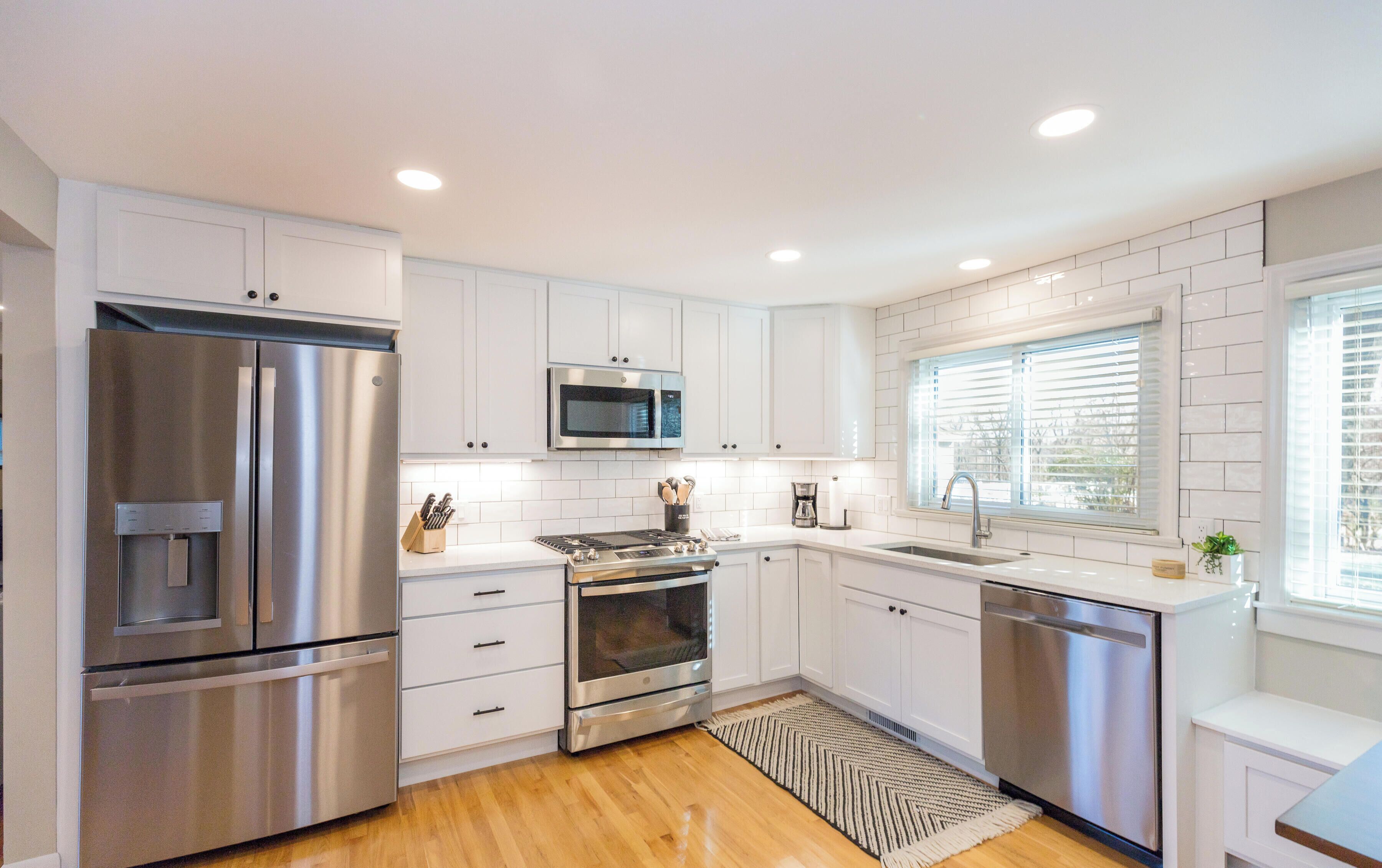 A modern kitchen with white cabinetry, stainless steel appliances, a microwave, and a dishwasher.