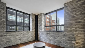 A modern room with exposed brick walls, large windows, and a round black table.