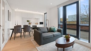 A modern living room with a grey sofa, a round coffee table, and a dining area with a glass table and chairs.