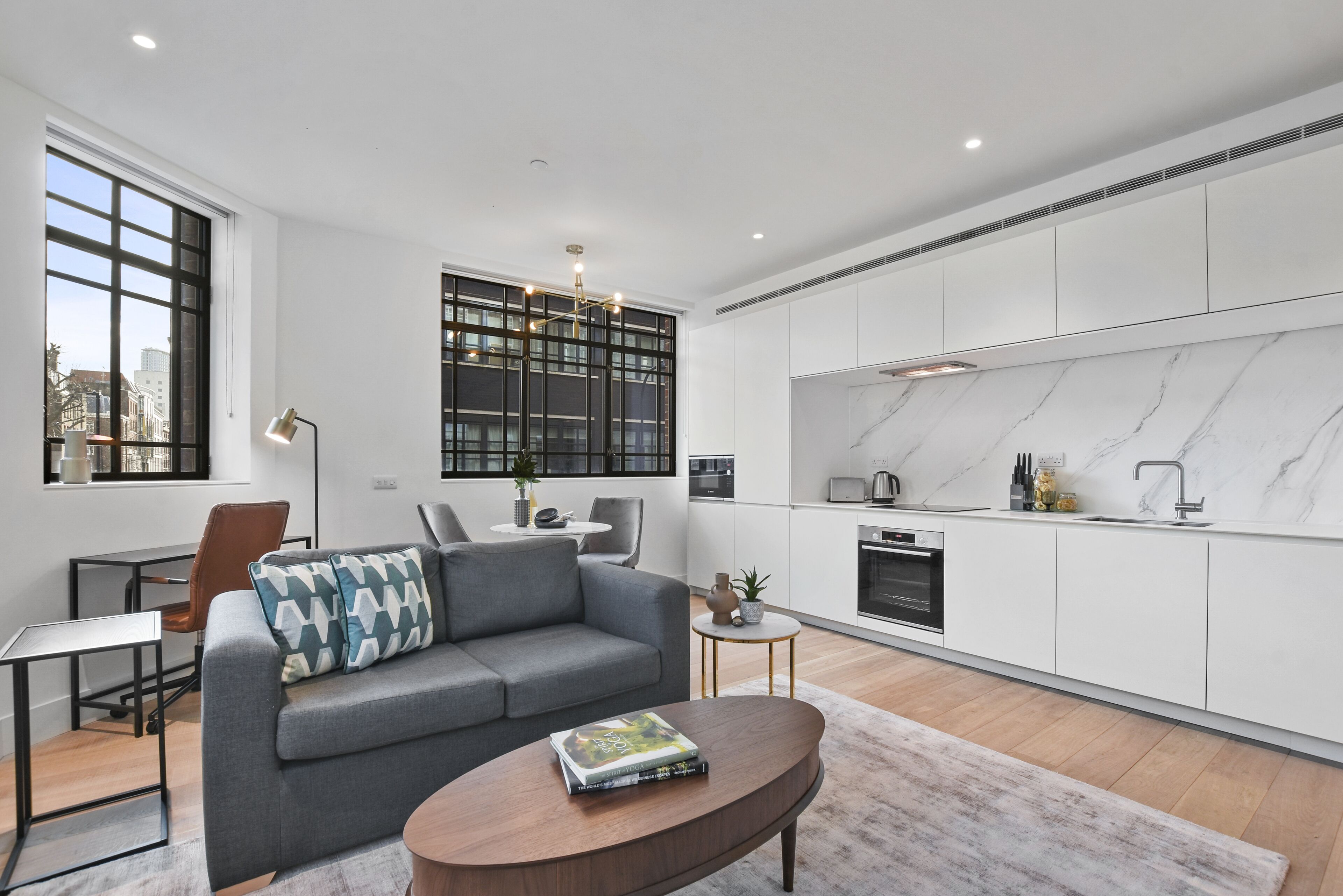 A modern living room with a grey sofa, a coffee table, and a bookshelf.