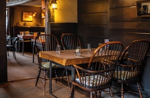A wooden dining table with chairs, a bench, and a wall-mounted light fixture in a restaurant setting. - The Green Man (Hereford)