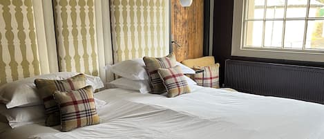 Una cama bien hecha con un cojín escocés, un cabecero de diseño vertical y una ventana con vistas.