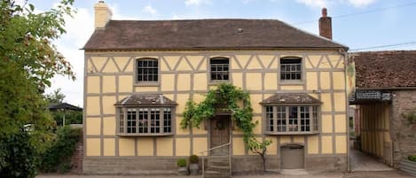 A traditional half-timbered building with a central entrance, two side windows, and a small porch area.