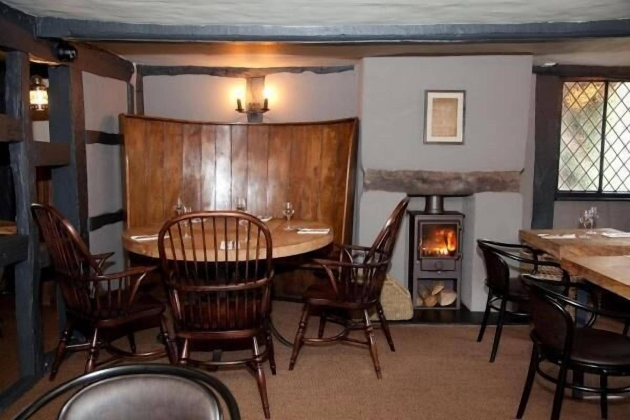 Un rincón comedor acogedor con una mesa redonda y sillas de madera, una chimenea de piedra y una ventana con vistas.