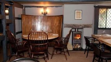 Un rincón comedor acogedor con una mesa redonda y sillas de madera, una chimenea de piedra y una ventana con vistas.