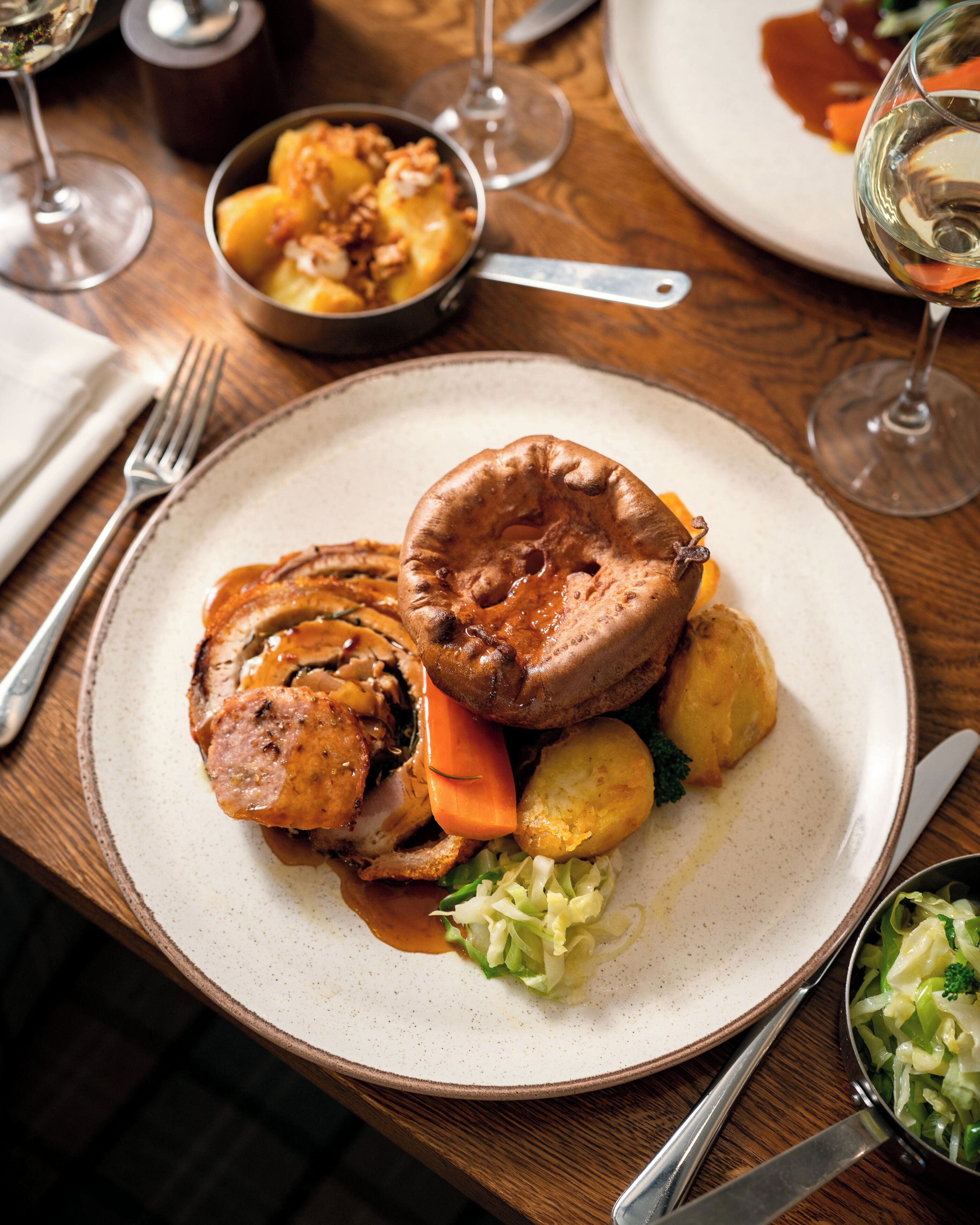 A plate of food with a Yorkshire pudding, meat, vegetables, and gravy.