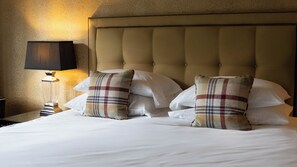 A bed with white linens, two plaid pillows, a headboard, and a bedside lamp. - The Green Man (Hereford)