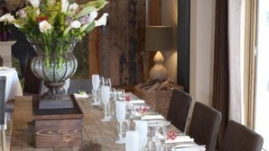 Een eettafel gedekt met wit servies en een vaas vol bloemen.