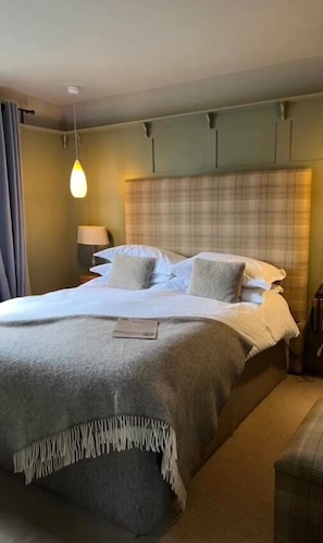 A neatly made bed with a plaid headboard, a bedside lamp, and a small table with a lamp. - The Green Man (Hereford)