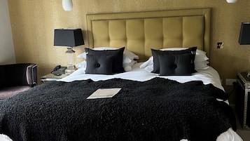 Une chambre d’hôtel avec un grand lit, une tête de lit, deux lampes de chevet et un sol recouvert de moquette.