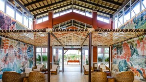 A lobby with wicker furniture, a central bench, and a tropical mural.