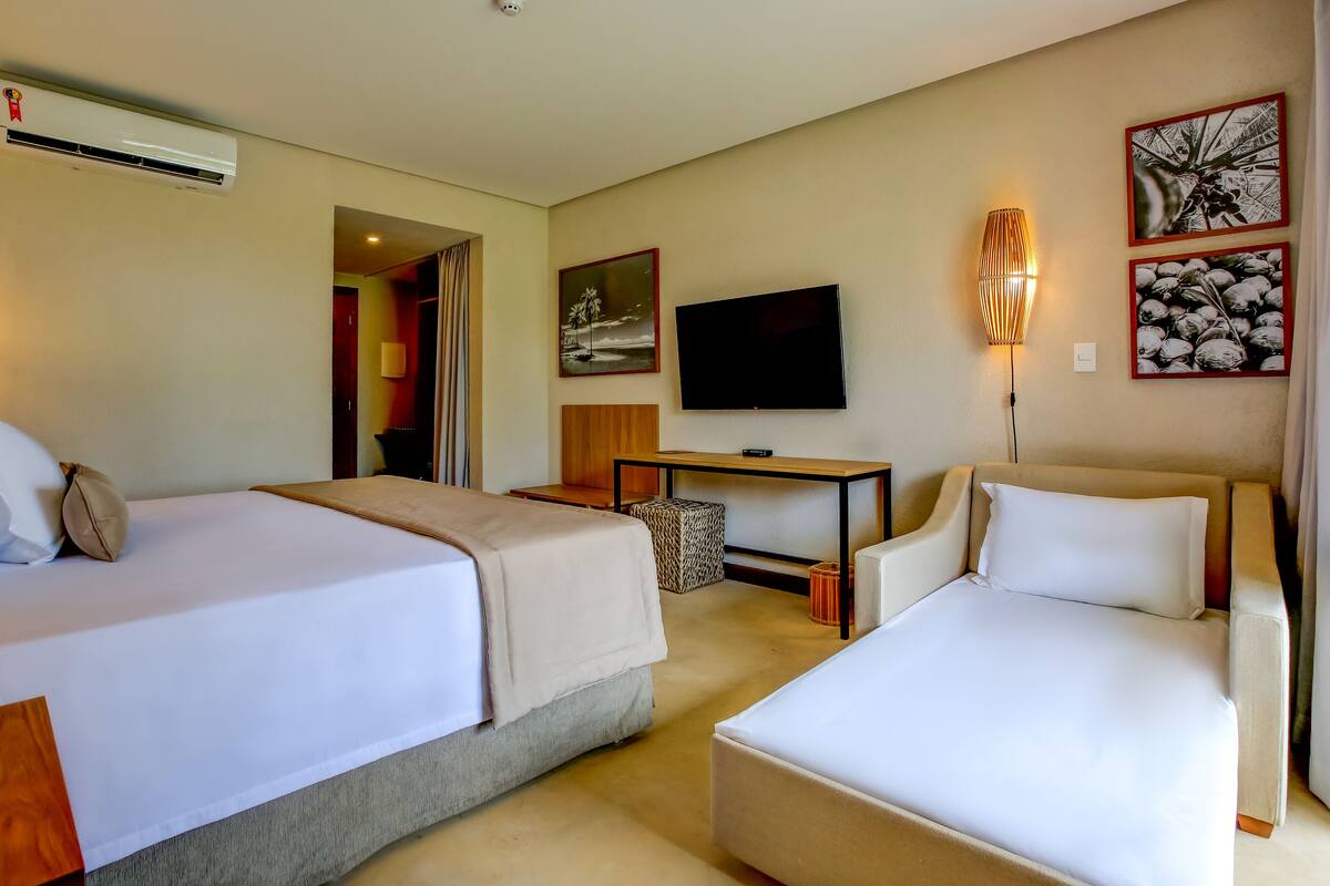 A hotel room with two beds, a TV, a desk, and a chair.