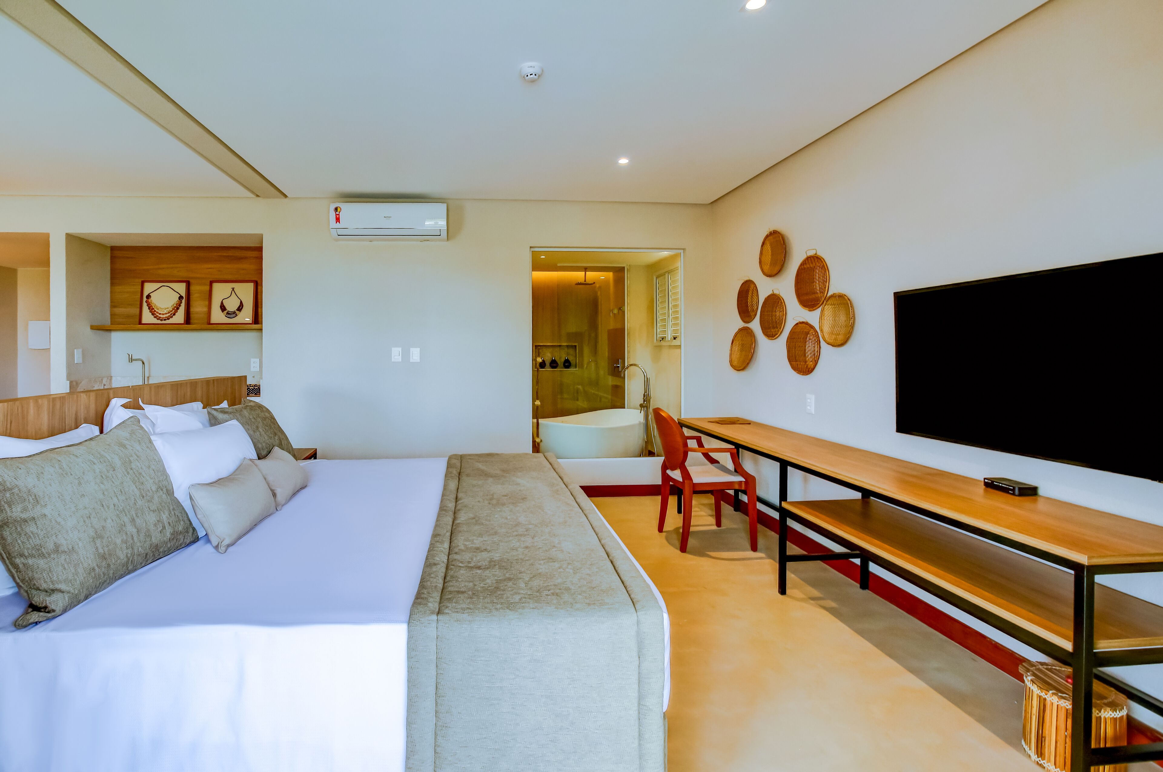 Una habitación de hotel moderna con una cama grande, un escritorio, un televisor de pantalla plana y un baño visible a través de una puerta abierta.