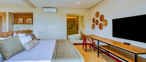 Una habitación de hotel moderna con una cama grande, un escritorio, un televisor de pantalla plana y un baño visible a través de una puerta abierta.