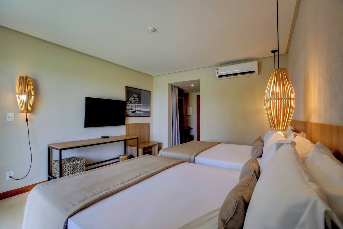 Habitación de hotel con dos camas, televisión, escritorio y lámpara.