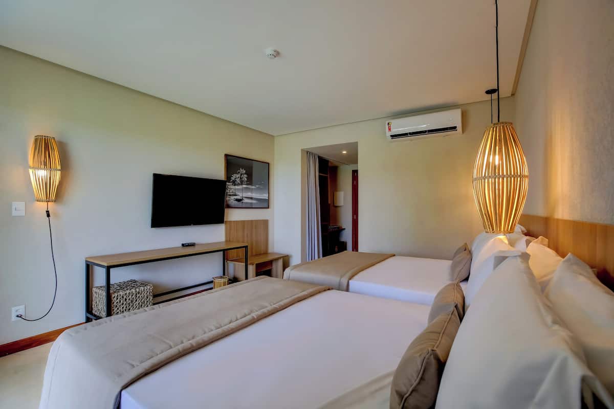Ein Hotelzimmer mit zwei Betten, einem Fernseher, einem Schreibtisch und einer Lampe.