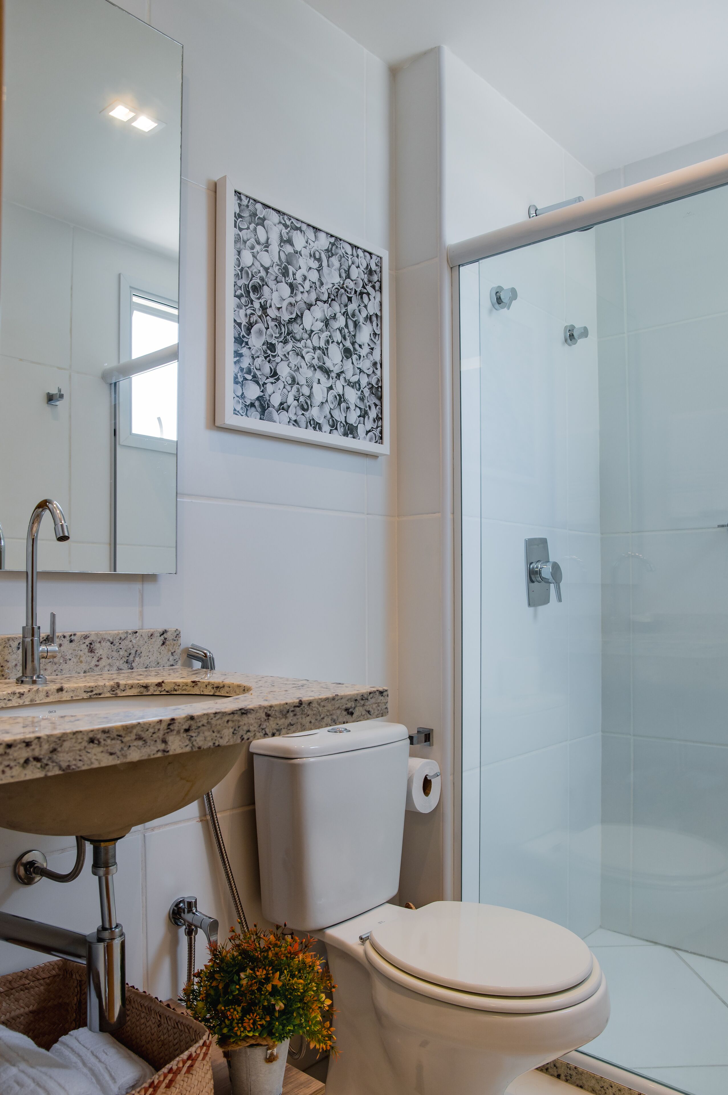 Un baño moderno con lavamanos de granito, inodoro, ducha y un espejo grande.