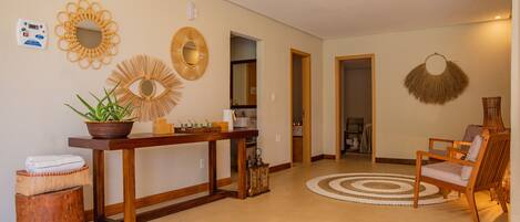 A spacious hallway with a wooden bench, a round rug, and decorative wall mirrors.
