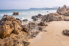 A rocky beach with large boulders and a sandy area.