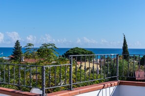 Uma varanda com vista para o mar e vegetação ao redor.