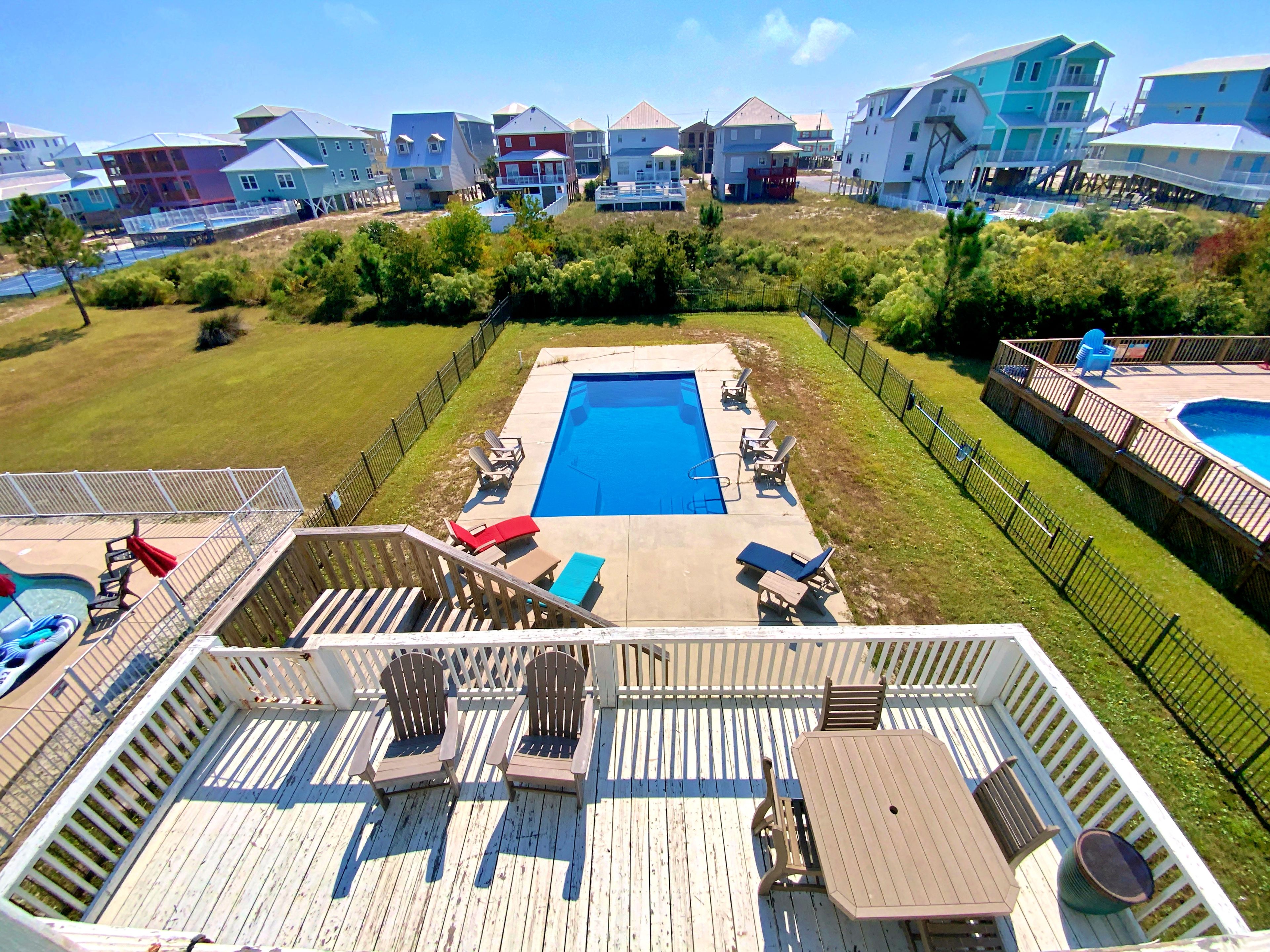 A residential area with a swimming pool, deck chairs, and a wooden deck.