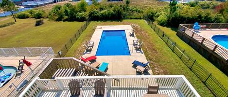 A residential area with a swimming pool, deck chairs, and a wooden deck.