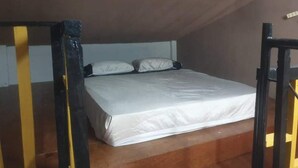 Ein Einzelbett in einem kleinen, abgeschlossenen Raum mit schrägem Dach.