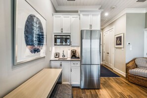 A modern kitchen with white cabinets, a stainless steel refrigerator, and a microwave.