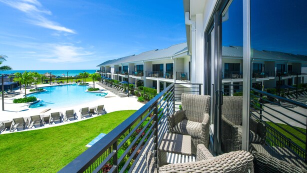 A hotel with a pool, lounge chairs, and a view of the ocean. - Anna Maria Beach Resort (Holmes Beach)