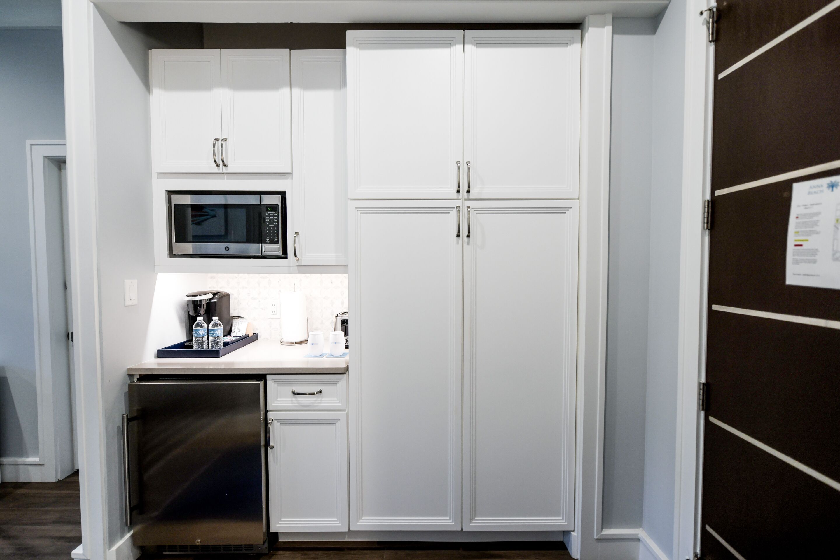 A compact kitchen with white cabinetry, a built-in microwave, and a small refrigerator.