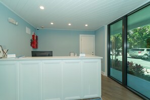 A reception area with a light blue wall, a white reception desk, a fire extinguisher, and a door.