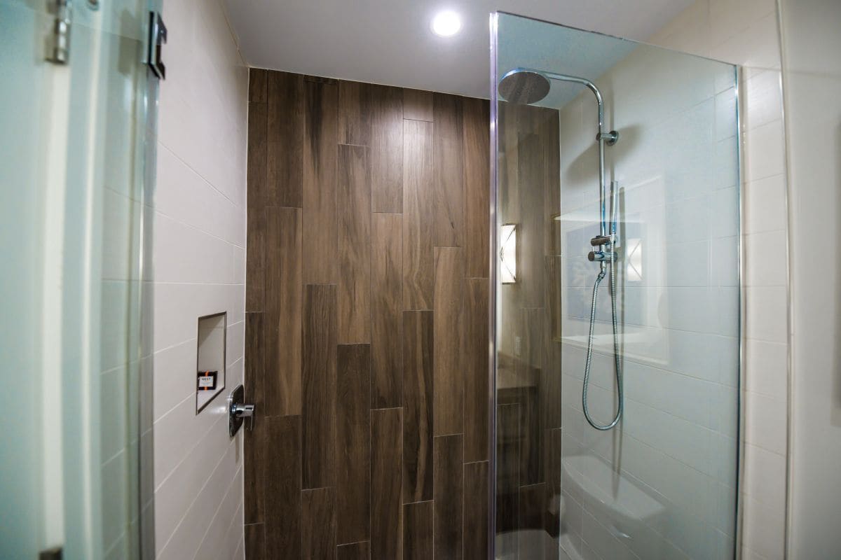 Une salle de bain moderne avec une douche à parois de verre, un lambris en bois et un carrelage au sol.