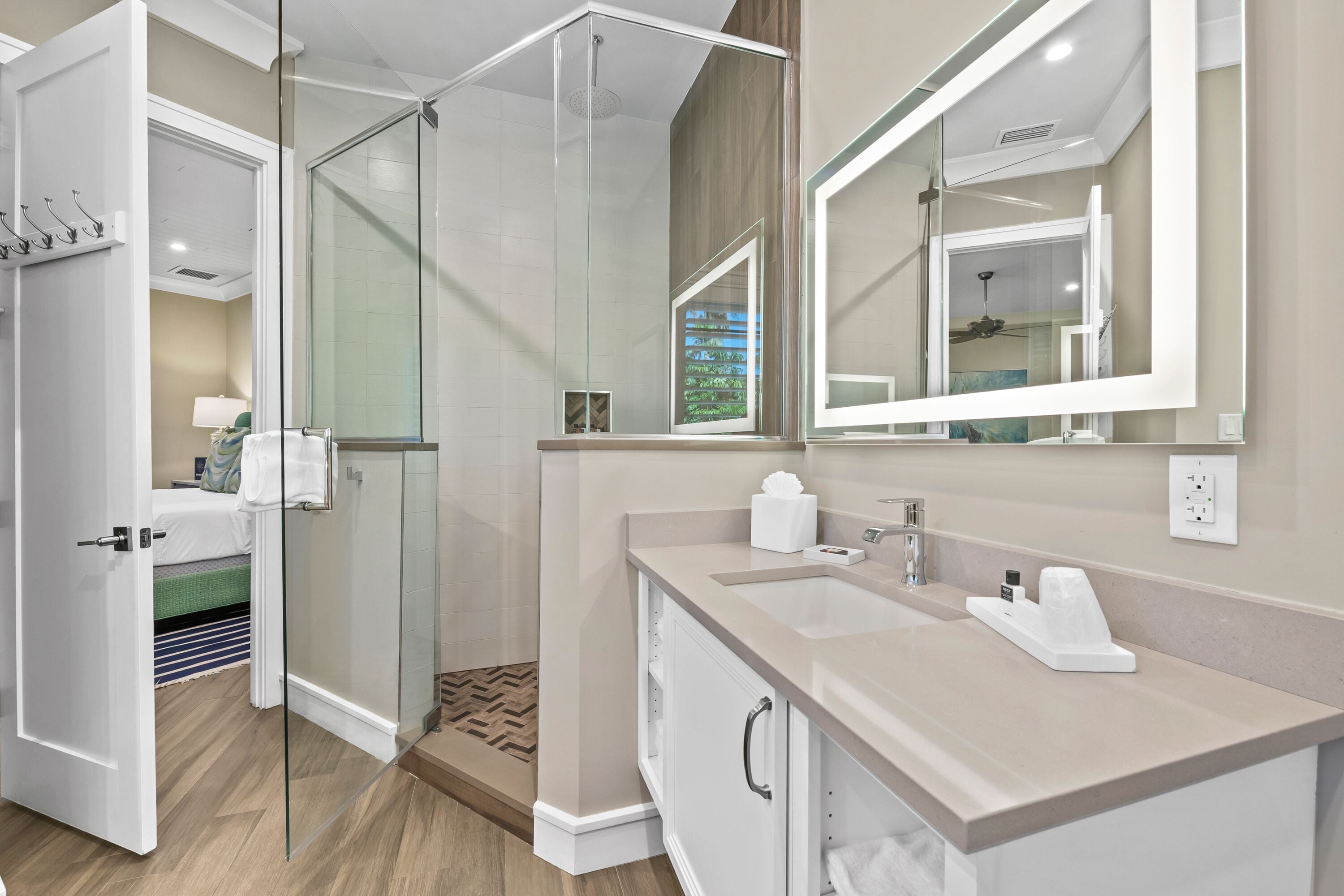 A modern bathroom with a glass shower enclosure, a large mirror, and a vanity with a sink and towel rack.