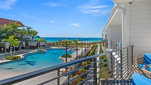 A pool area with lounge chairs and umbrellas, a view of the beach, and a clear sky. - Anna Maria Beach Resort (Holmes Beach)