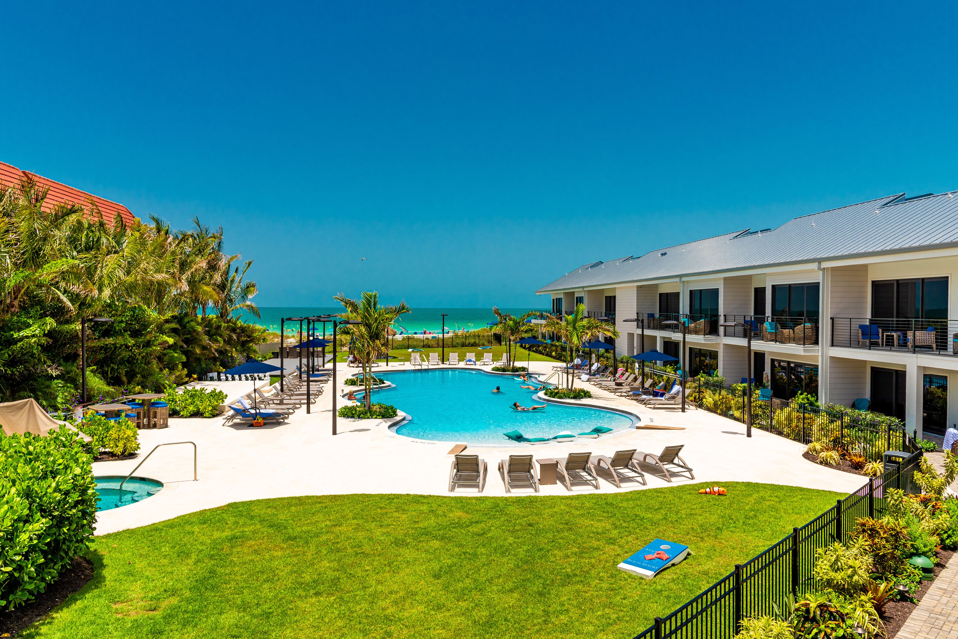 A pool area with lounge chairs, a small pool, and a view of the ocean.
