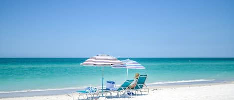 Am Strand, weißer Sandstrand, Liegestühle, Sonnenschirme
