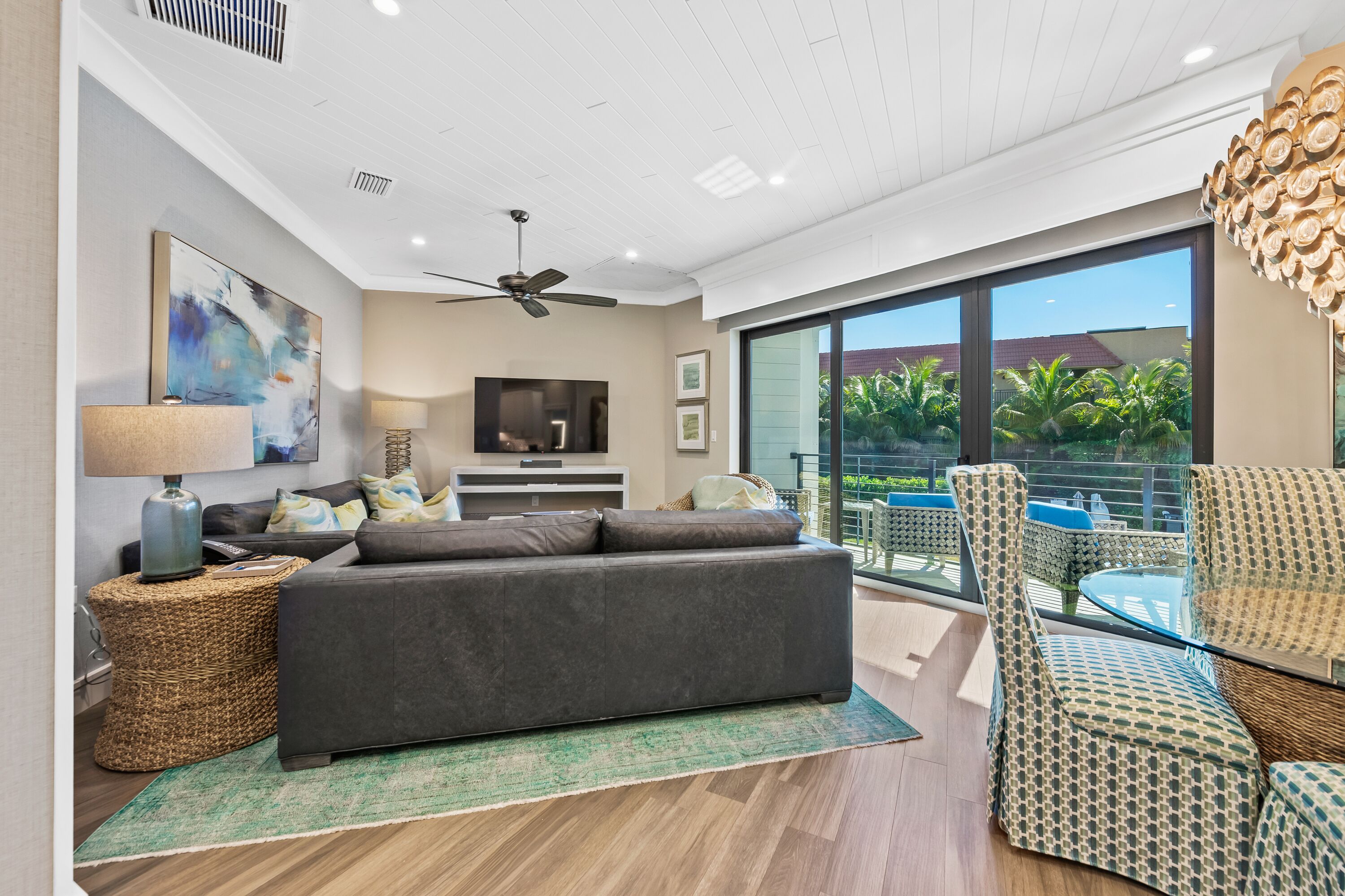 A modern living room with a grey sofa, a TV, and a ceiling fan.