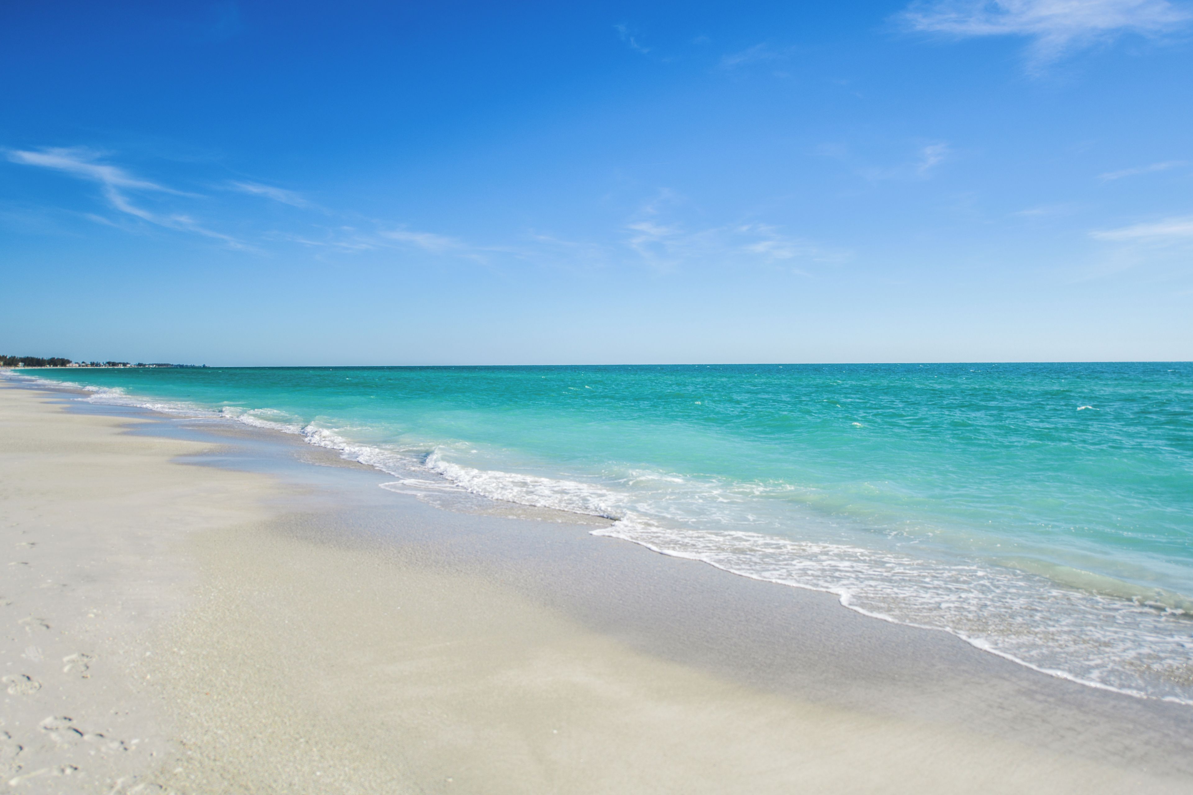 Een strand met helder turquoise water en wit zand.