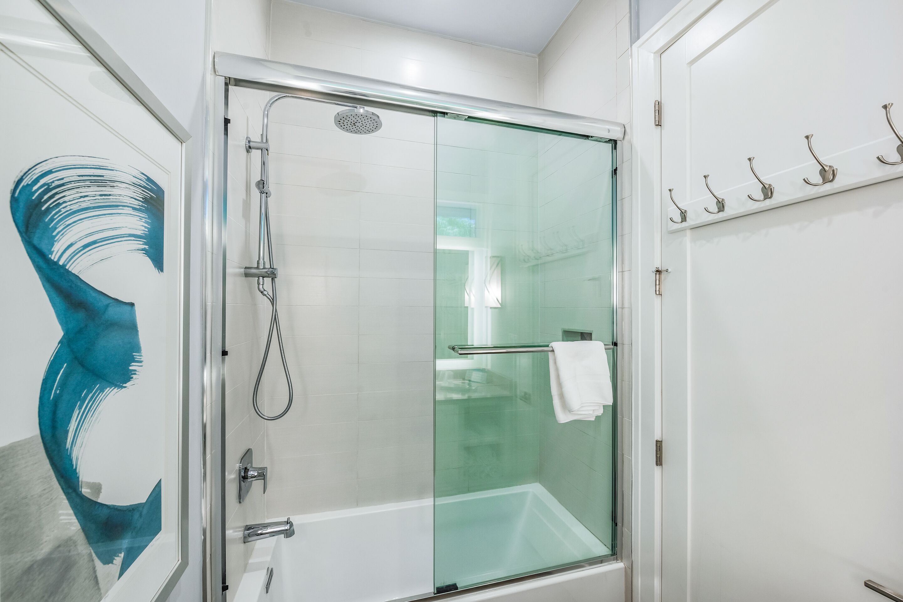 Ein modernes Badezimmer mit einer Duschkabine aus Glas, einer weißen Badewanne und einer Glastür.