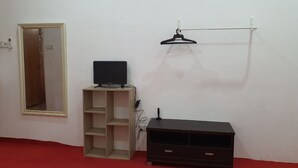 A room with a mirror, a TV on a wooden stand, a coat rack, and a red carpet. - Hotel O Z Dirgahayu 313 (Kota Bharu)