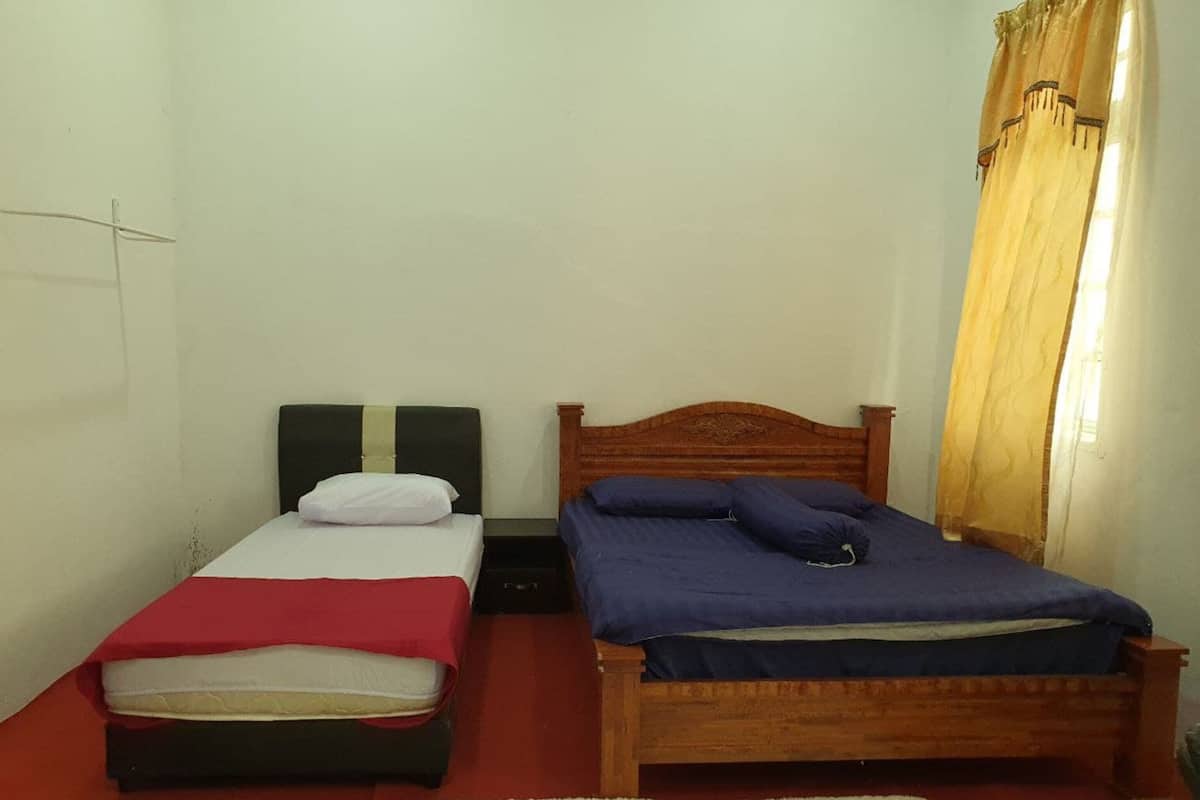 Ein Zimmer mit zwei Einzelbetten, einem kleinen Tisch und einem roten Teppich.