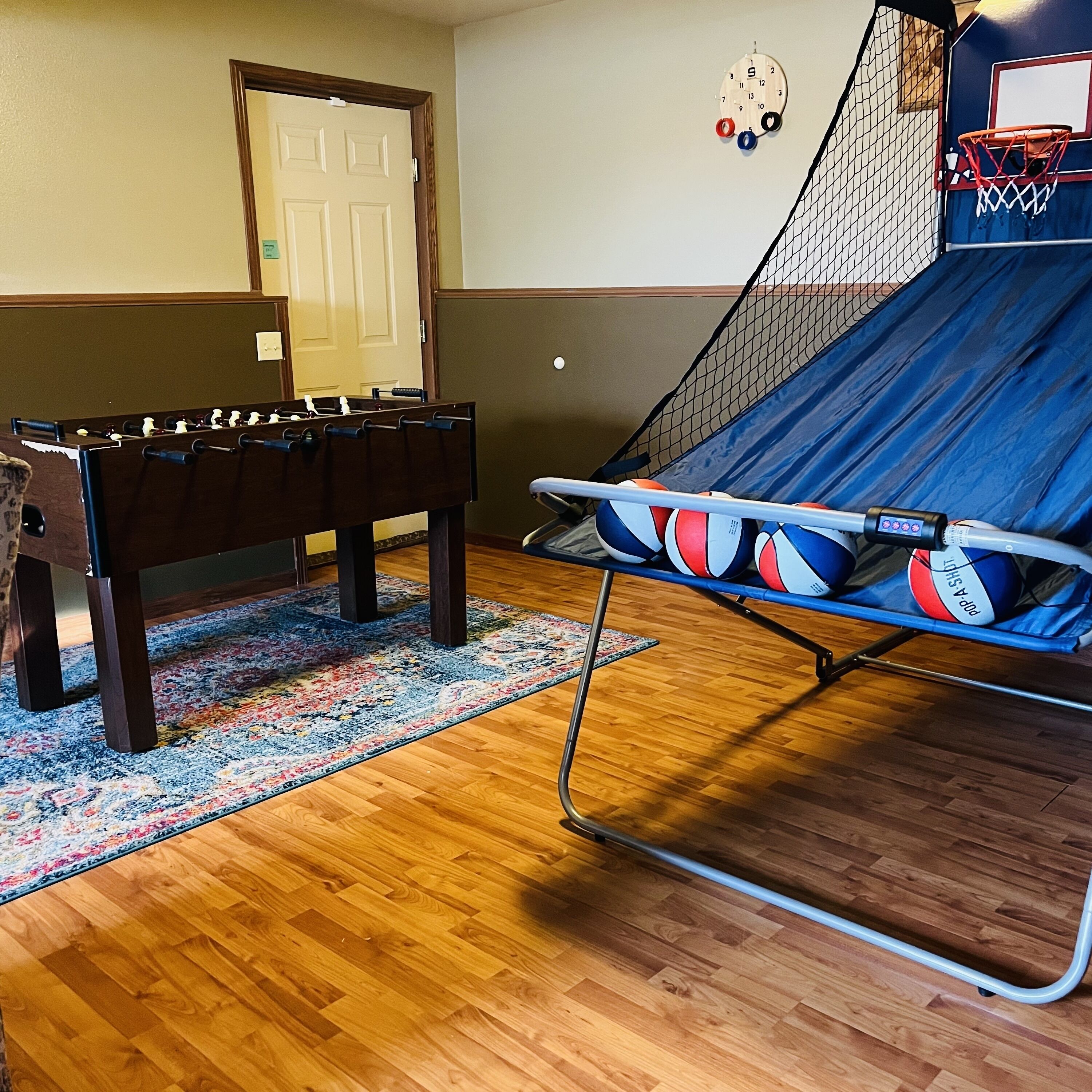 Une pièce équipée d’un baby-foot, d’un trampoline avec des ballons de basket et d’un panier de basket.
