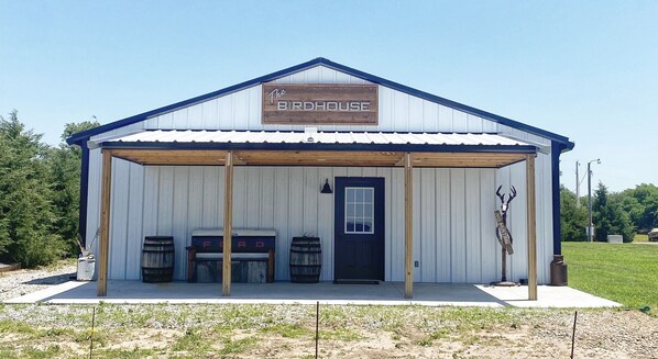 A small building with a sign reading "The Birdhouse." It has a blue door, two barrels outside, and a wooden structure over the entrance. - Cozy with plenty of room (Saint John)