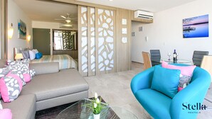 Una habitación de hotel moderna con sofá, sillón, una mesita de vidrio y una cama con vistas.