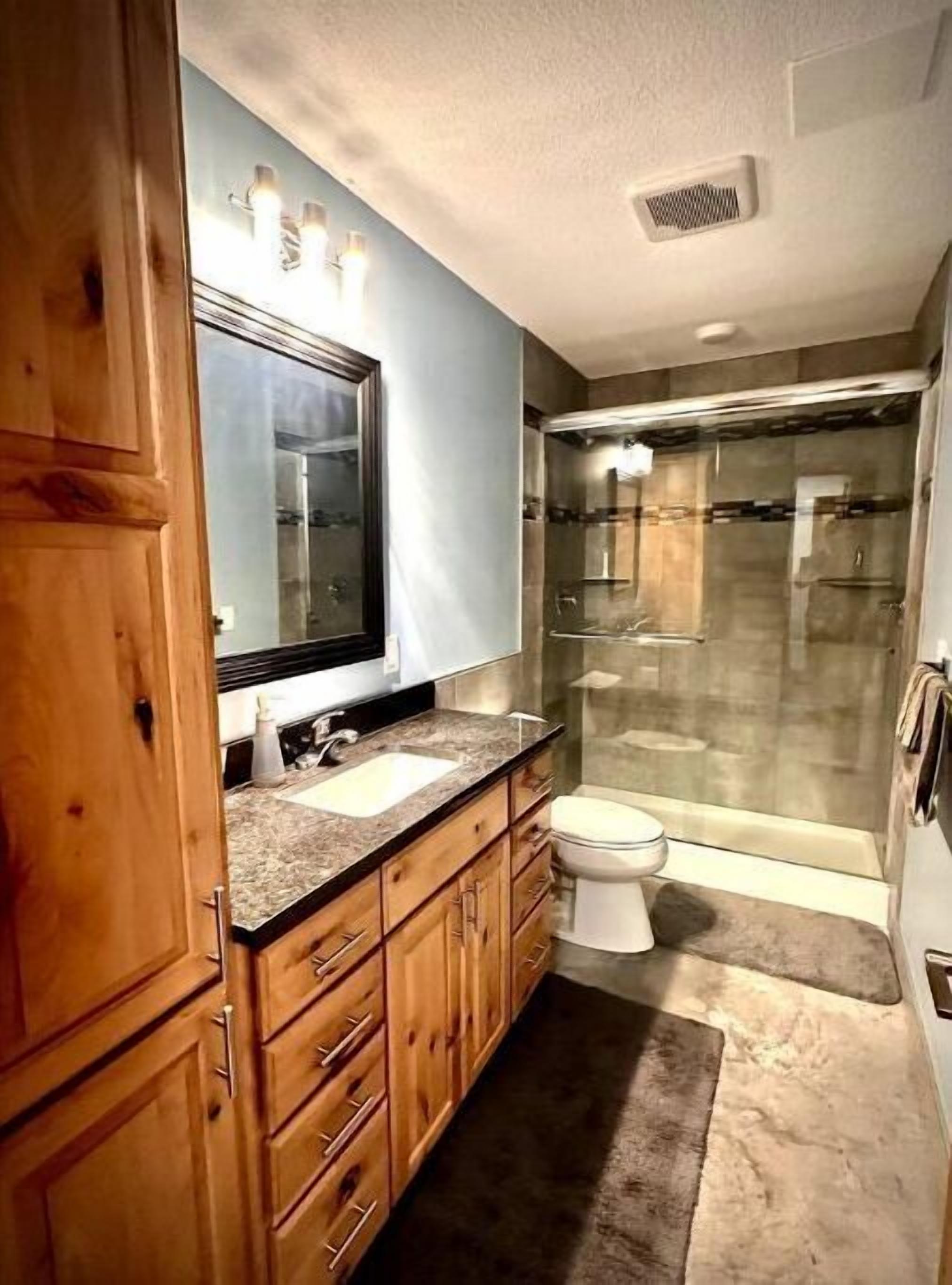 Ein modernes Badezimmer mit einem Holzwaschtisch, einer Duschkabine aus Glas und einer weißen Toilette.