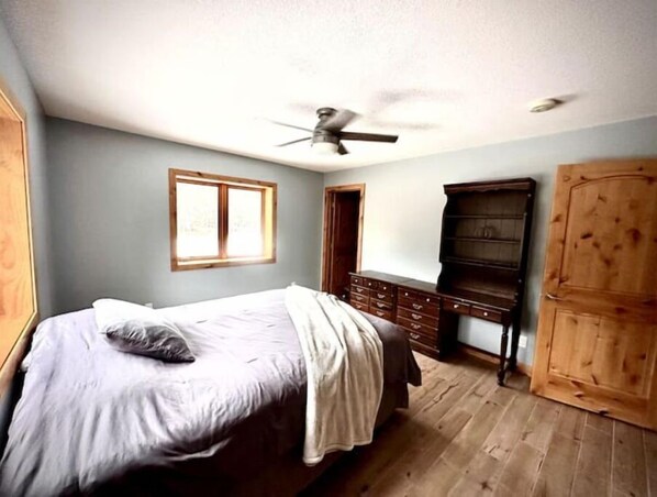 A bedroom with a bed, a dresser, a wardrobe, and a ceiling fan.